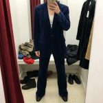 A person wearing a yellow and blue plaid velvet suit in a dressing room.